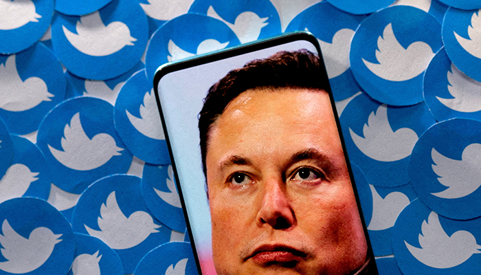 An image of Elon Musk is seen on a smartphone with the Twitter logo printed on it in this photo illustration taken on April 28, 2022.  - Reuters