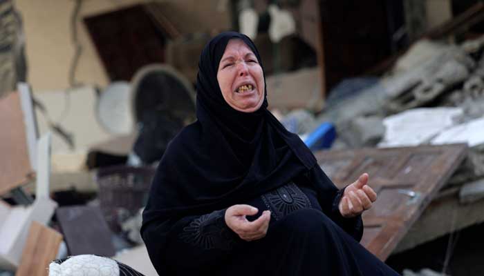 A Palestinian woman reacts as she sits amidst the rubble of her home, destroyed during overnight Israeli air strikes in Gaza City on August 7, 2022. Photo: AFP
