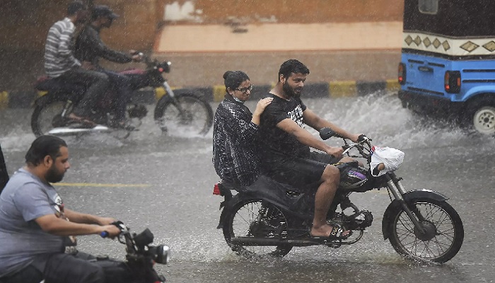 Commuters ride motorbikes along a street during monsoon rains in Karachi. Photo: AFP