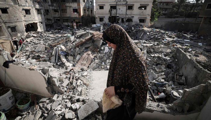 A Palestinian woman checks the damage as she walks through rubble in front of her home in Gaza city early on August 8, 2022, following a cease fire between Israel and Palestinian militants. Israel agreed last night to an Egyptian proposed truce with in Gaza with Islamic Jihad after three days of intense conflict. — Photo by Mahmud Hams/AFP
