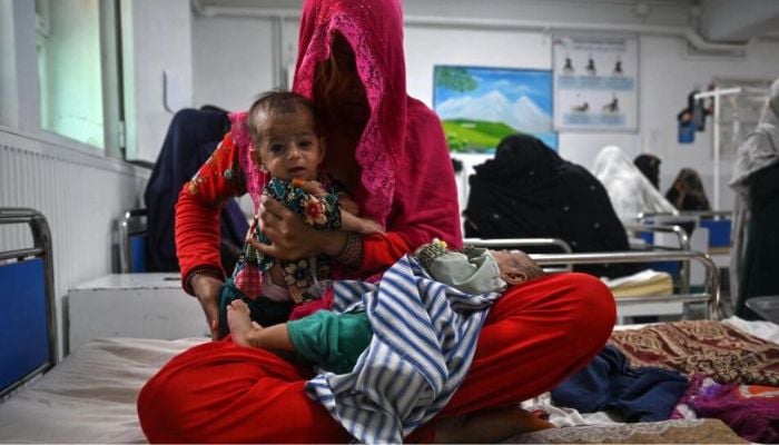 Breshna sits on a hospital bed with her four-month-old twins Subhania and Subhan in the malnutrition ward at a hospital run by Doctors Without Borders (MSF), in Lashkar Gah Lillian — AFP