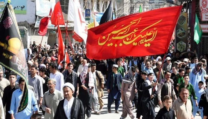 Mourners hold religious flags as they march during a procession on the tenth day of Muharram in Quetta. — AFP