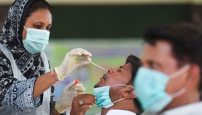 A health official collects a swab sample from a teacher to test for the COVID-19 coronavirus at a government school following the governments announcement to reopen educational institutes starting from September 15, in Karachi on September 14, 2020. — AFP