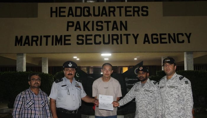 چینی شہری، زو ژیانگ وی، (درمیان میں) 10 اگست 2022 کو کراچی میں پاکستان میری ٹائم سیکیورٹی ایجنسی کے اہلکاروں کے ساتھ تصویر بنا رہے ہیں۔ - PMSA
