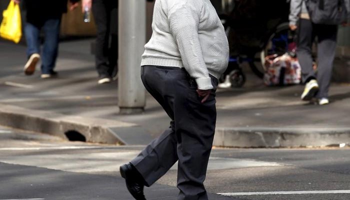 A man crosses a main road as pedestrians carrying food walk along the footpath in central Sydney, Australia, August 12, 2015. — Reuters/File