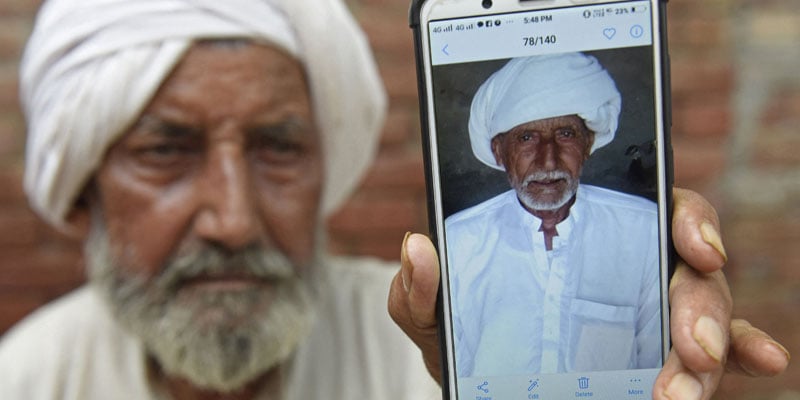 2 اگست 2022 کو لی گئی اس تصویر میں بھارتی سکھ مزدور سیکا خان اپنے بڑے بھائی صادق کو فون کی سکرین پر دکھا رہے ہیں۔  - اے ایف پی