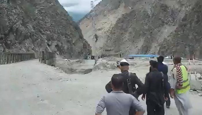 Locals look over as bridge gets swept away at Uchaar Nullah near Karakoram Highway. — Twitter Screengrab/sherryrehman