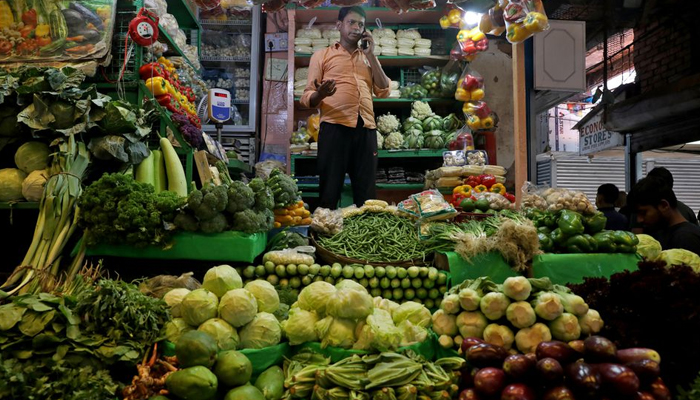 A vegetable vendor speaks on his mobile phone at a retail market area in Kolkata, India, March 22, 2022. — Reuters