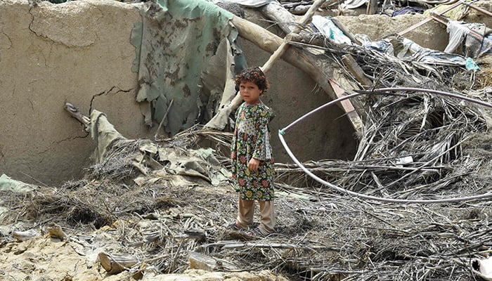 A girl stands over the debris of a damaged mud house at a flood-affected town called Gandawah in Jhal Magsi district, southwestern province of Balochistan, Pakistan on August 2, 2022. — AFP