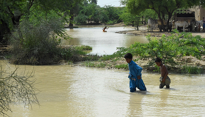 Children wade across at a flood-affected town called Gandawah in Jhal Magsi district, southwestern province of Balochistan, Pakistan on August 2, 2022. — AFP