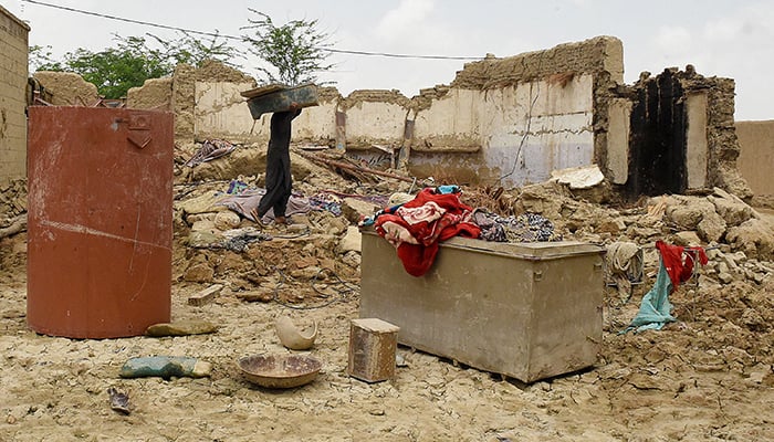 A local resident takes belongings from his damaged mud house at a flood-affected town called Gandawah in Jhal Magsi district, southwestern province of Balochistan, Pakistan on August 2, 2022. — AFP