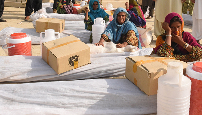 Local residents receive relief supplies near their damaged houses at a flood-affected town called Gandawah in Jhal Magsi district, southwestern province of Balochistan, Pakistan on August 2, 2022. — AFP