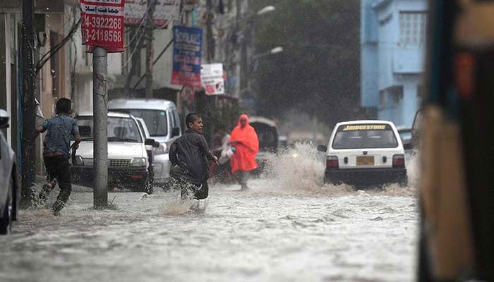 Image shows children running in accumulated rainwater as heavy downpour lashed different parts of Karachi.— INP