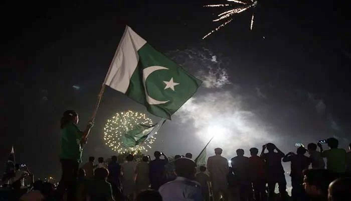 Citizens carry national flags as they watch fireworks in Islamabad on August 14 to mark the countrys Independence Day. — AFP/File