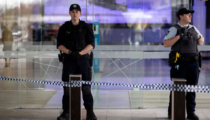 Police stand guard at the entrance of a terminal after a gunman opened fire at the airport in Canberra on August 14, 2022. — AFP