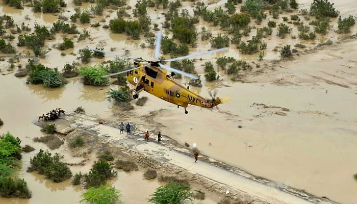Pakistan Navy personnel drop ration and relief goods through helicopter for the people stranded in a village in district Lasbela. — INP/File