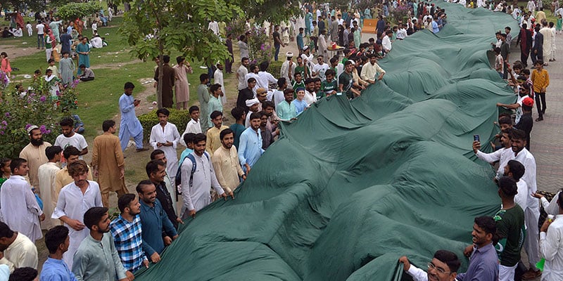 People hold large sized national flag to at a ceremony. — Online