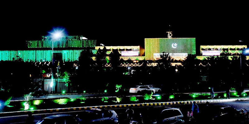Buildings in the red zone of Islamabad illuminated with green and white lights. — NNI