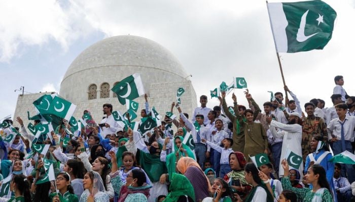 Attendees wave Pakistans flag while singing national songs during a celebration of the countrys 75th Independence Day at the mausoleum of Muhammad Ali Jinnah in Karachi.— Reuters