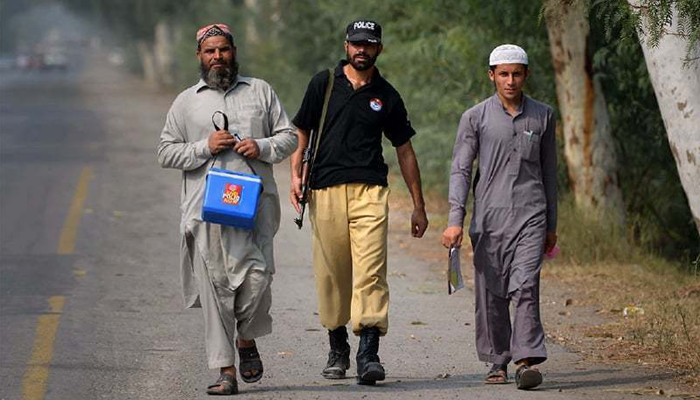 In this file photo, a policemen accompanies polio workers on an immunisation campaign. — Reuters/File