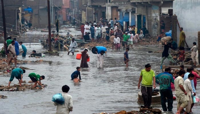 People wade through a flooded residential area after heavy monsoon rains. — AFP/File