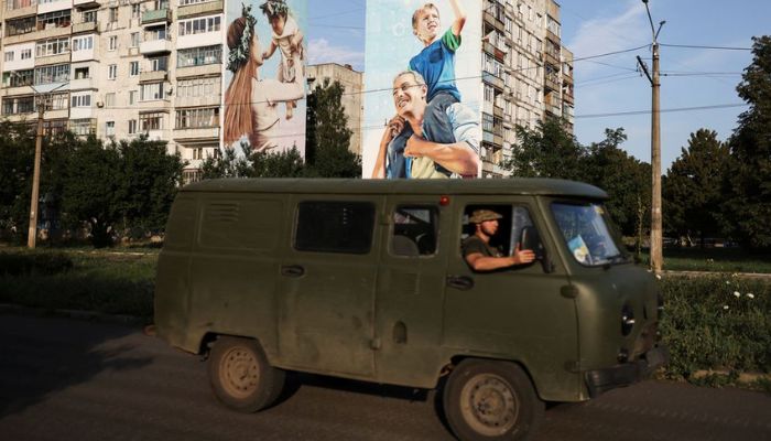 Ukraine servicemen drive past a mural of a family on damaged buildings in Bakhmut, as Russias invasion of Ukraine continues, in Donetsk region, Ukraine August 14, 2022. — Reuters