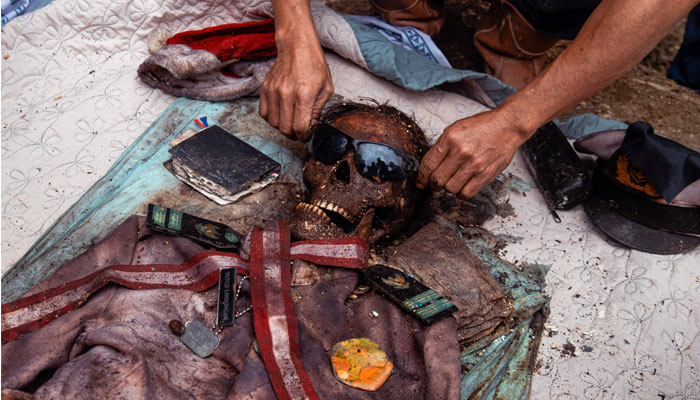 This picture taken on August 16, 2022 shows members of the Toraja ethnic group preparing the body of an exhumed relative from a community burial site, to be cleaned and dressed in a series of traditional ceremonies honouring the dead known asManene, in Torea village in North Toraja, Indonesia´s South Sulawesi. In a village on Indonesia´s Sulawesi island, residents pull coffins holding the preserved bodies of their loved ones from a burial cave carved into the mountainside in a ritual for the afterlife. — AFP