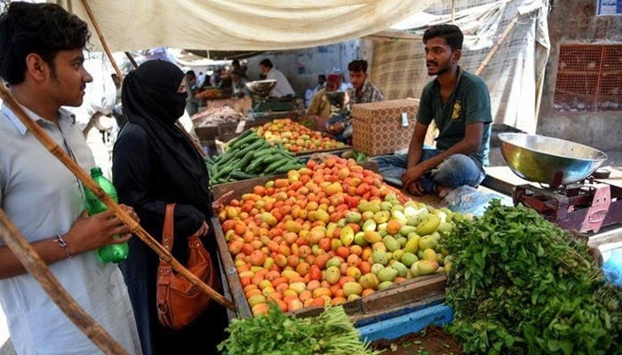 A vegetable seller can be seen selling fresh vegetables to consumers. — AFP/File