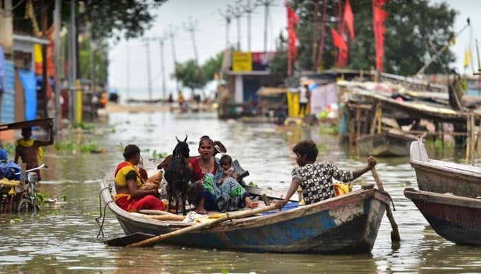 Flood-affected residents of a low lying area on the banks of the River Ganges move their belongings to drier ground on a boat at Daraganj area in Allahabad on August 19, 2022. — AFP/File