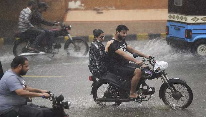 Commuters ride motorbikes along a street during monsoon rains in Karachi. Photo: AFP/file