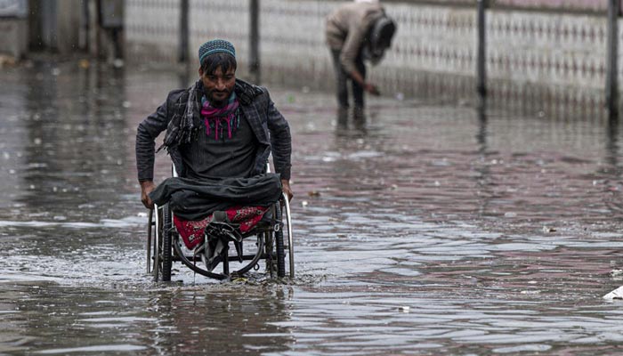 A man on a wheelchair makes his way through flood waters after heavy rains in Kabul on April 24, 2022 AFP/File