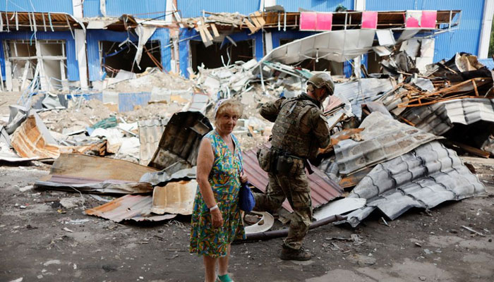21 اگست 2022 کو یوکرین کے ڈونیٹسک کے علاقے باخموت میں ایک خاتون تباہ شدہ شاپنگ سینٹر کے پاس کھڑی ہے، جب یوکرین میں روسی حملہ جاری ہے۔ — رائٹرز