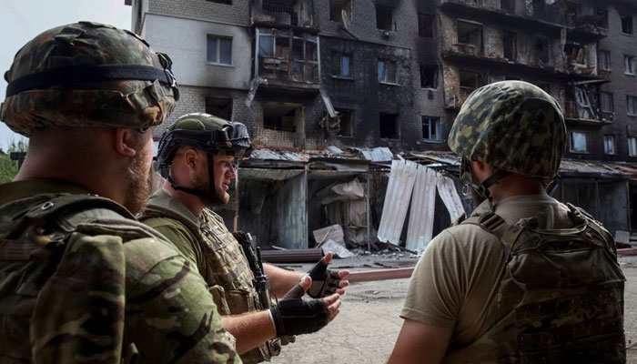 Ukrainian service members speak to each other in front of a residential building damaged by a Russian military strike, amid Russias attack on Ukraine, in the town of Siversk, Donetsk region, Ukraine August 20, 2022. — Reuters