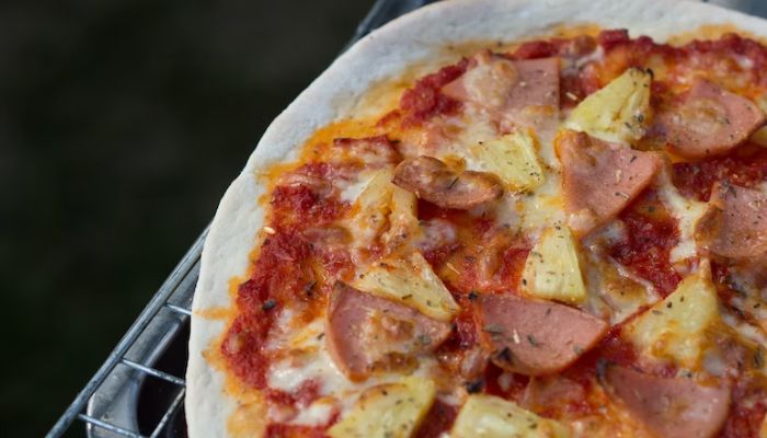 Baked pizza with pineapple and ham topping. — Unsplash