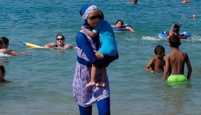 A woman wearing a burkini walks in the water August 27, 2016 on a beach in Marseille, France, the day after the countrys highest administrative court suspended a ban on full-body burkini swimsuits that has outraged Muslims and opened divisions within the government, pending a definitive ruling. —  Reuters
