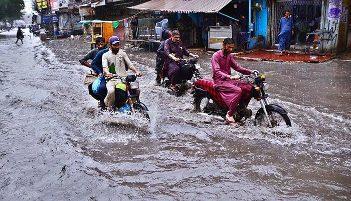 Motorcyclists passing through rainwater accumulated at Kazi Qaiyoum Road after heavy rain in Hyderabad. — APP/File