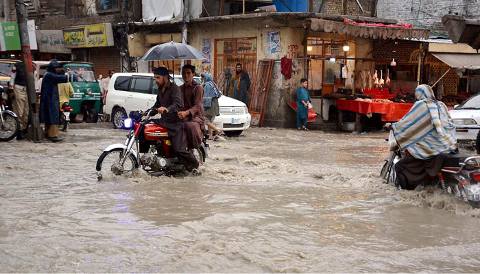 Two motorcyclists wade through the flooded streets. — INP