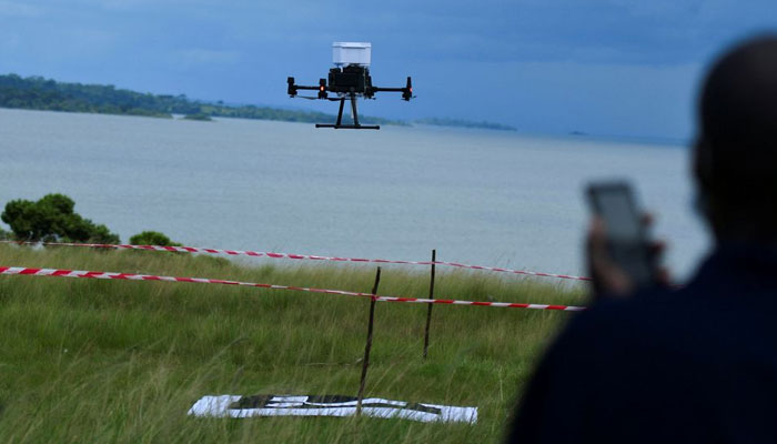 A member of a village health team monitors a drone mounted with a medicine cool box in Kalangala district, Uganda. — Reuters