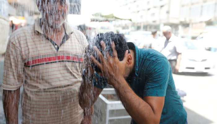 A man washes his face to cool off from the scorching summer heat in Baghdad. — Reuters