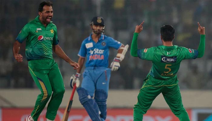 (L-R) Pakistans Wahab Riaz and Mohammad Amir celebrate after taking a wicket of Indias Ajinkiya Rahane. — AFP/File