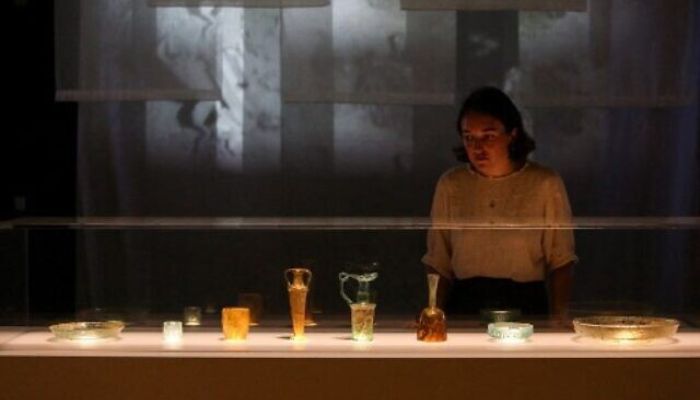 British museum press assistant Stella Scobie examines the newly conserved ancient glass vessels damaged during the 2020 Beirut port explosion, and displayed at the British Museum in London, on August 24, 2022 — AFP