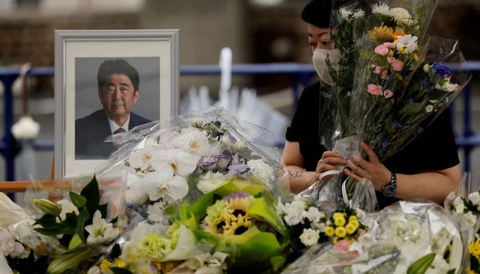 A mourner offers flowers next to a picture of late former Japanese Prime Minister Shinzo Abe, who was shot while campaigning for a parliamentary election, on the day to mark a week after his assassination at the Liberal Democratic Party headquarters, in Tokyo, Japan July 15, 2022. — Reuters