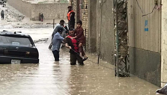 A rescue official carries a child after heavy rains lash parts of Pakistan in August, leaving hundreds dead. — Radio Pakistan