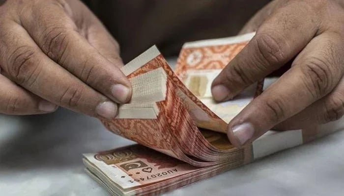 A currency dealer is counting Rs5,000 notes. — AFP/File