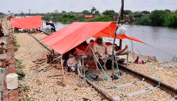 Rain effected people sitting on a safe area after heavy rain at Mirpurkhas Road. — APP