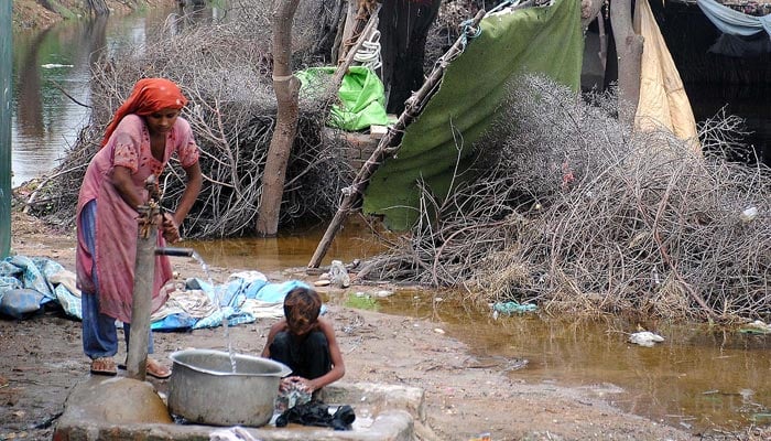 Rain affected washing their cloths after makeshifts on Tando Jam road. — INP