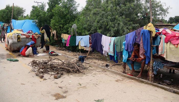 Millions affected by historic floods in Pakistan 64 Flood affected family living in temporary makeshifts alongside Tando Jam road. — Online