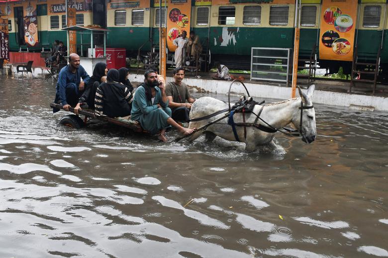 24 اگست کو پاکستان کے حیدرآباد میں مون سون کے موسم کے دوران بارشوں کے بعد لوگ سیلاب زدہ سڑک کے ساتھ گدھا گاڑی پر سوار ہو رہے ہیں۔ - رائٹرز