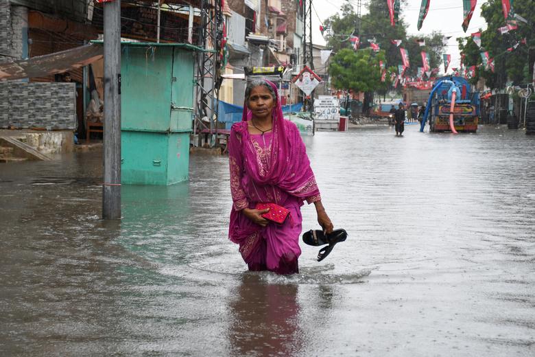 حیدرآباد، پاکستان میں 24 اگست کو مون سون کے موسم میں بارش کے بعد ایک خاتون سیلاب زدہ سڑک پر چل رہی ہے۔ — رائٹرز