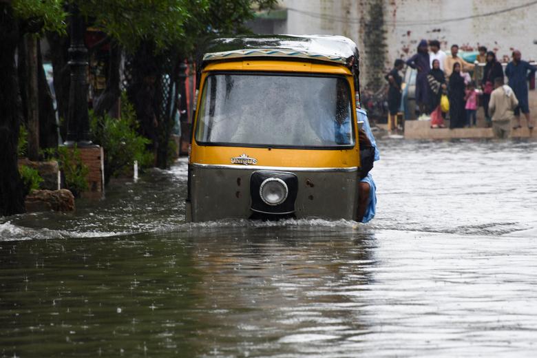 24 اگست کو پاکستان کے حیدرآباد میں مون سون کے موسم کے دوران بارشوں کے بعد سیلاب زدہ سڑک پر لوگ رکشہ (ٹوک ٹوک) پر سوار ہو رہے ہیں۔ — رائٹرز